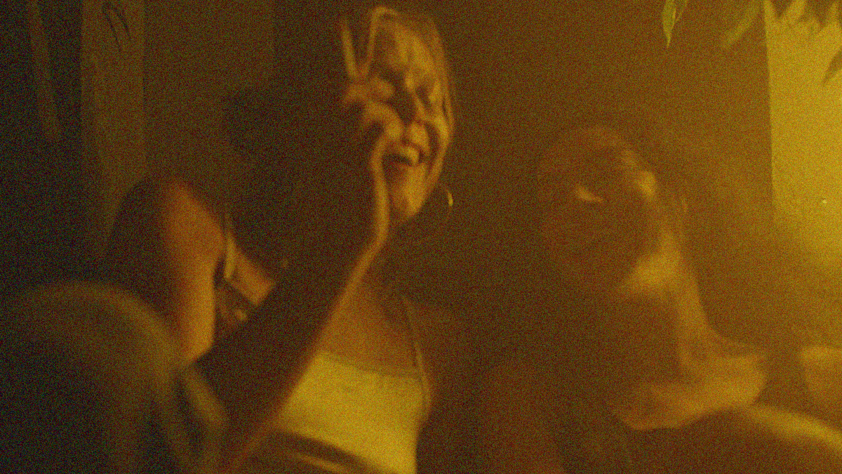 Two women laugh together in a dark yellow haze.