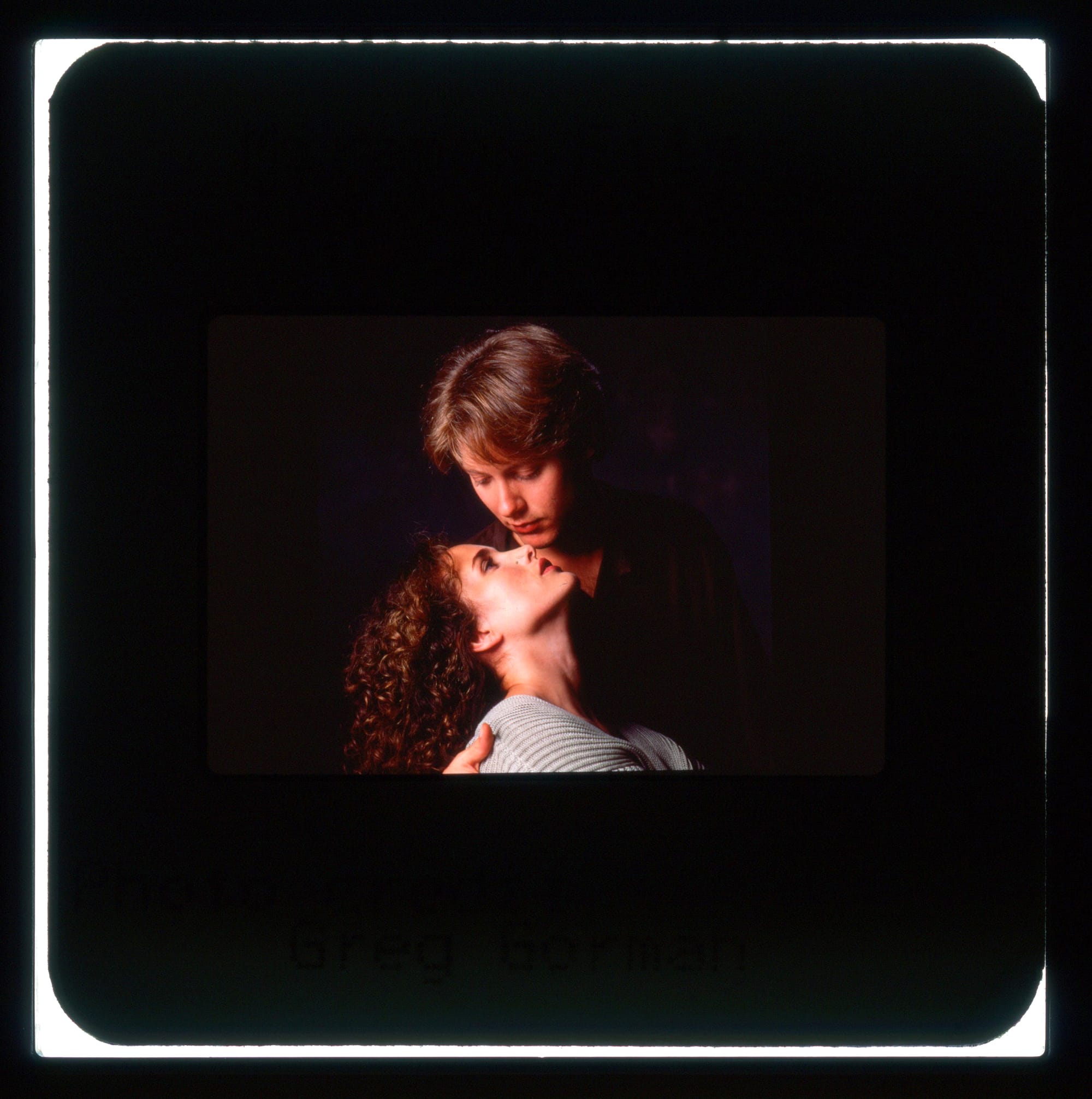 Color publicity slide: Close-up portrait pose with Spader looking down and leaning over MacDowell as she bends back and looks up.