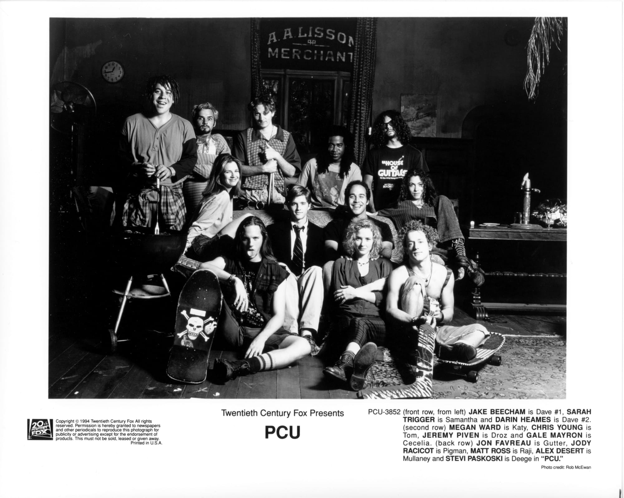 A group of co-eds pose around a couch in a darkened room with the words "A.A. LISSON MERCHANT" on the wall behind them. Some have skateboards. One has drum sticks. One has a goalie stick.