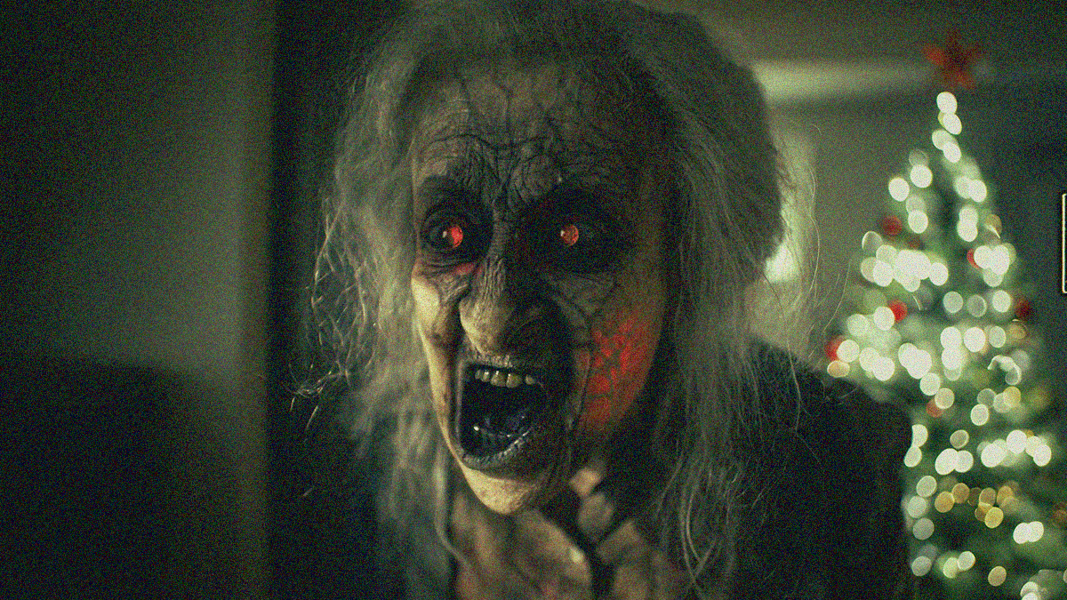 Close-up of an old woman's face contorting menacingly with black veins and glowing eyes.
