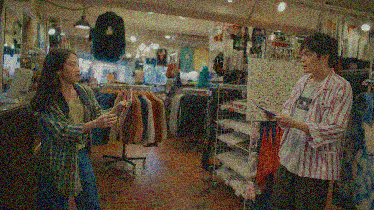 A woman on far left and man on far right look at each other in shock inside a vintage clothing store.