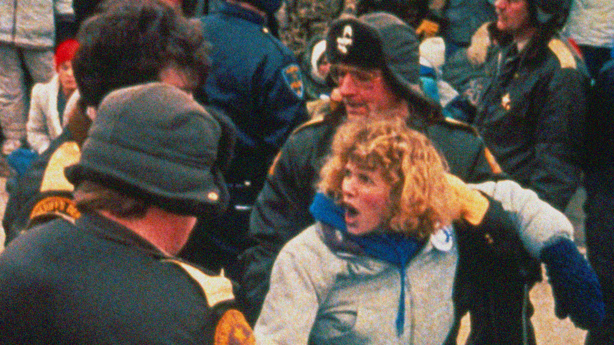 A woman is screaming as she's dragged away from a picket line by police.