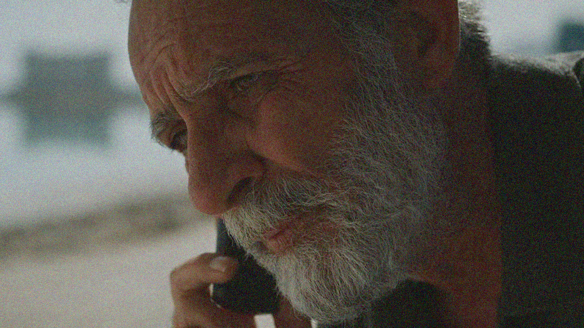 Close-up of an older bearded man with a cellphone to his ear.