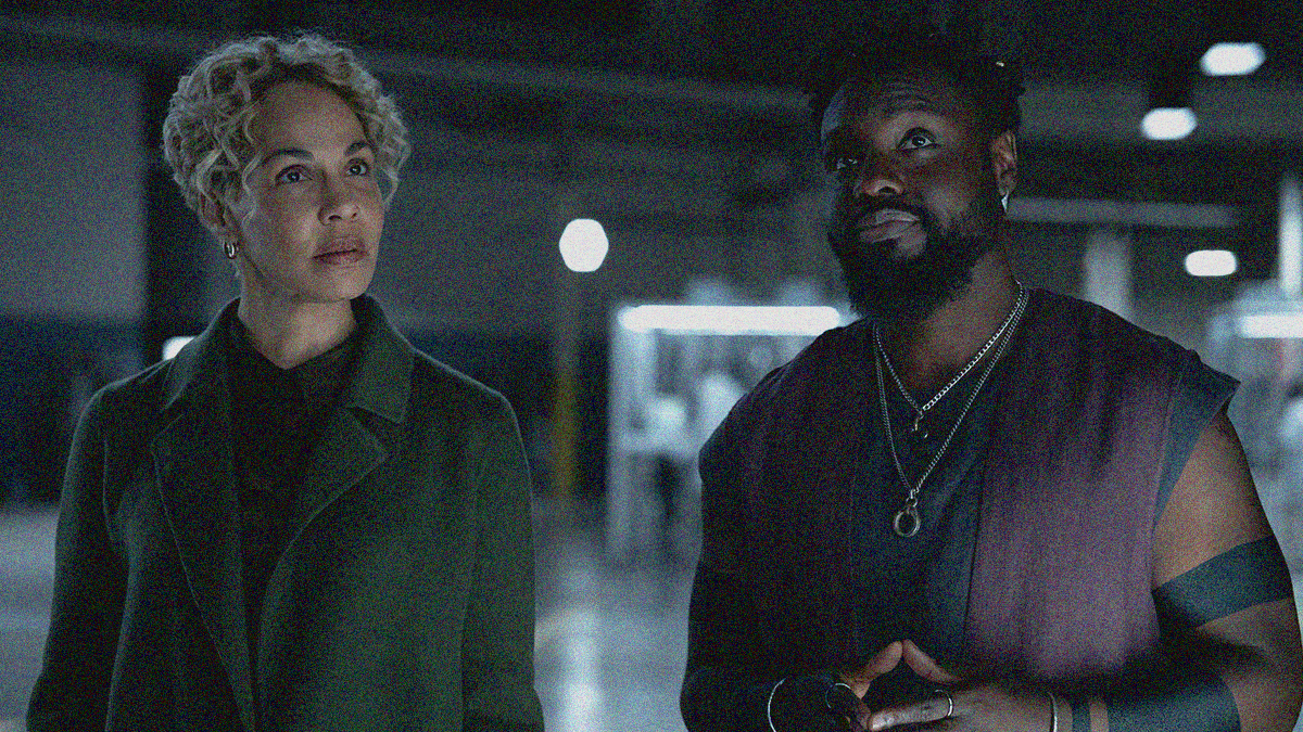Close-up of a woman (left) and man (right) from torso up. Both are looking upwards at something off-screen.