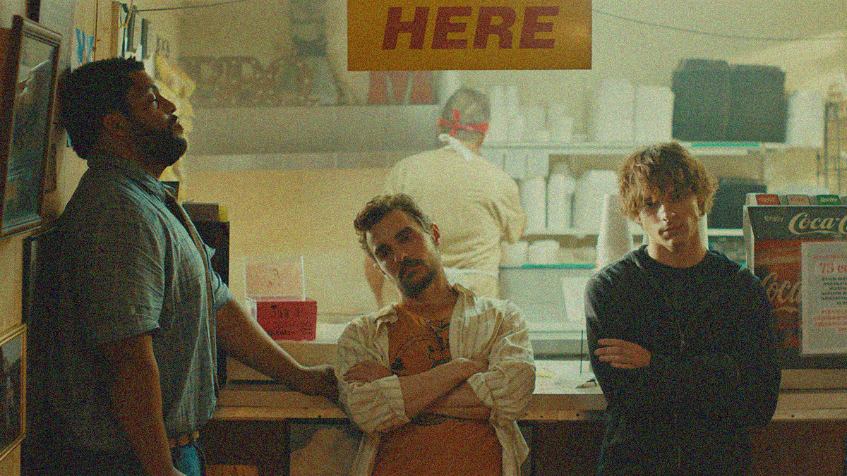 Three men looking dejected in front of a diner counter.