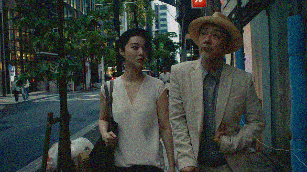 A young woman in white walks down a street with an older man in a hat.