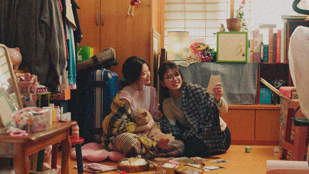 Two women sit on the floor looking at photographs.