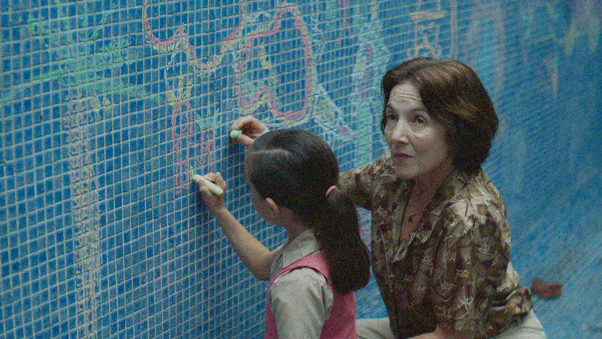 An older woman and her granddaughter draw on the tiles of a drain pool wall with chalk.