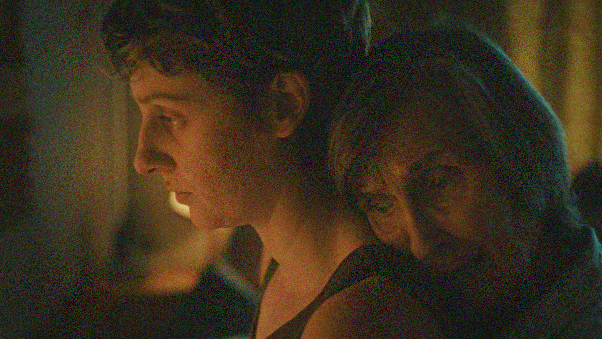 Close-up of a young woman in profile with an older woman resting her head on her back.