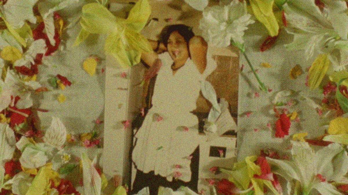 An old photograph of a woman smiling laid on a table with flowers covering the frame around it.