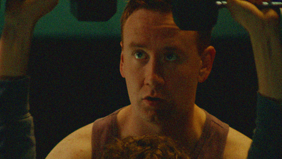 Close-up of a man spotting another as he lifts dumbbells above his head.