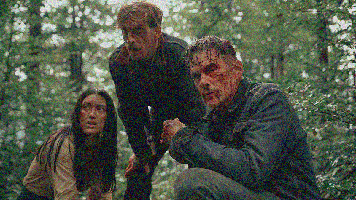 Two men and a woman, bloodied and beaten all, crouch in the woods and look off-screen left.