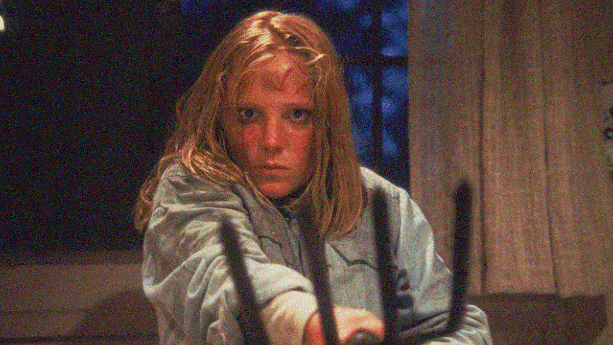 A young woman stares directly at the camera while holding up a pitchfork as though we're about to attack her.