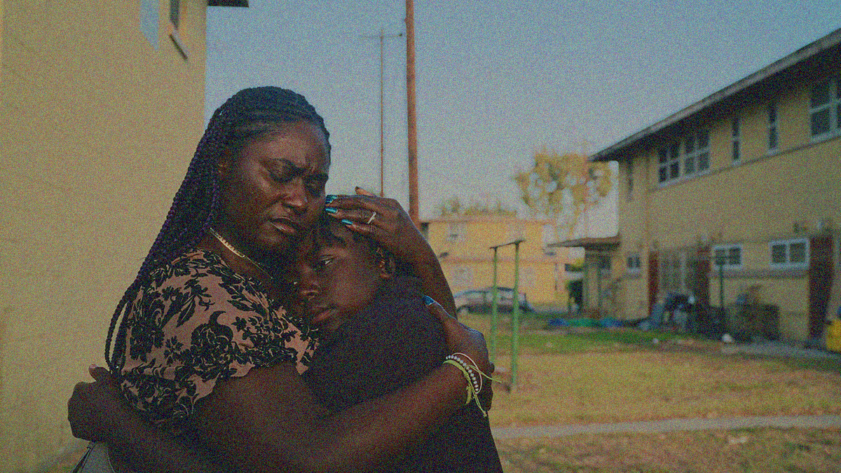 A Black mother and young son embrace outside.