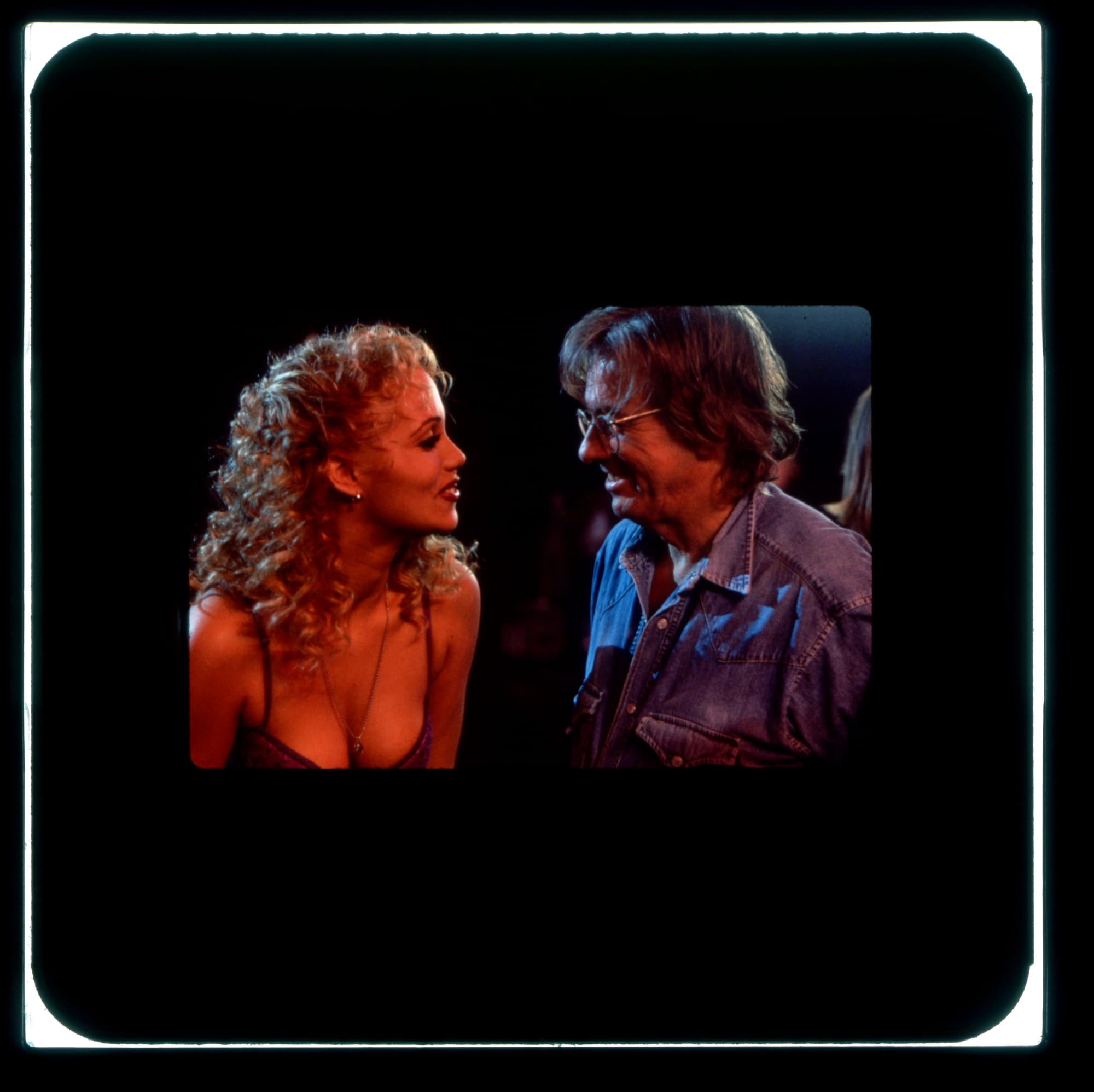 A woman on the left smiles looking at a man on the right, also smiling.