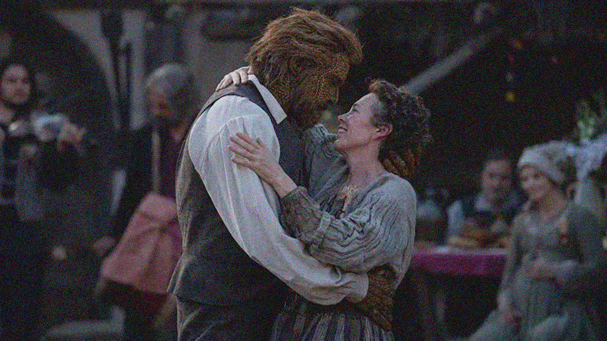 A man made of wicker and a woman dance with smiles at the center of the frame.