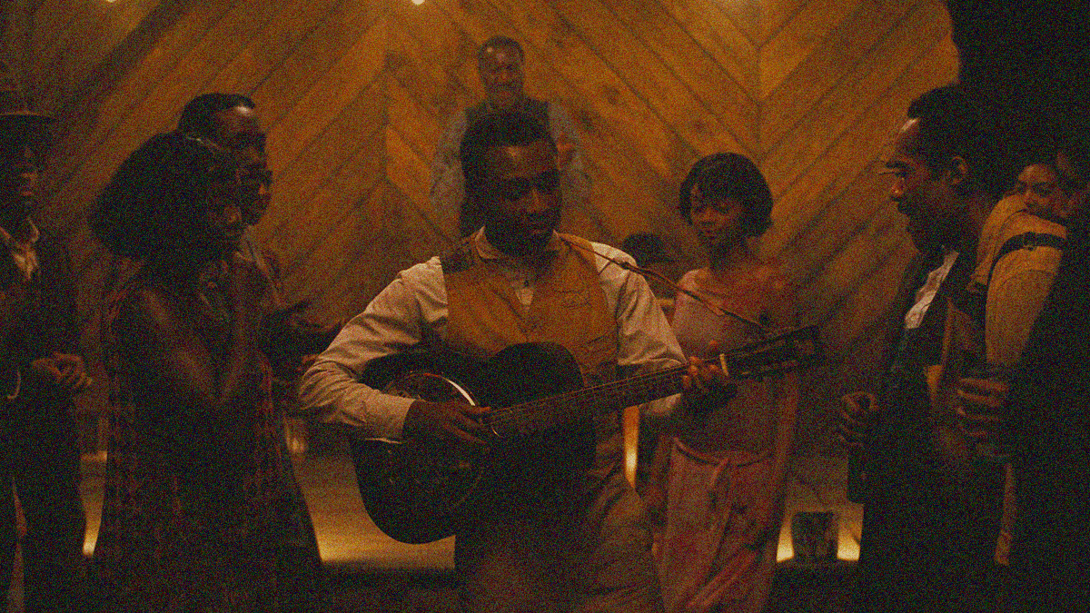 Miles Caton plays guitar center frame while people dance and listen around him.