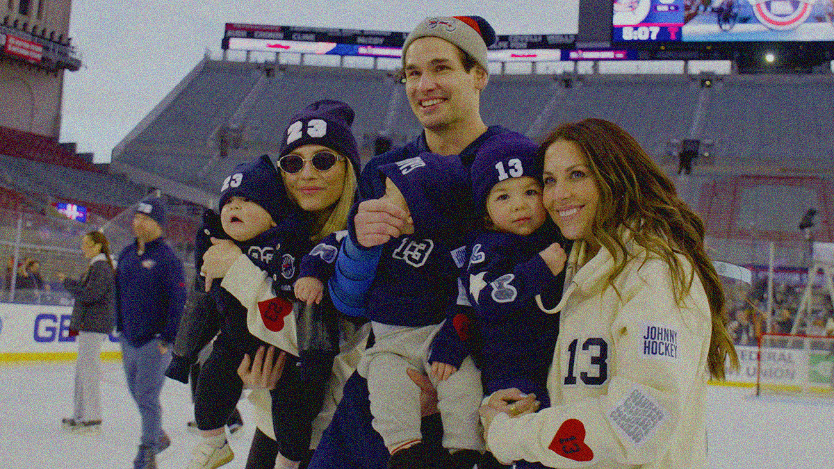 Sean Monahan in winter hat on ice, flanked by his wife and Johnny Gaudreau's widow and their children wearing their fathers' numbers.