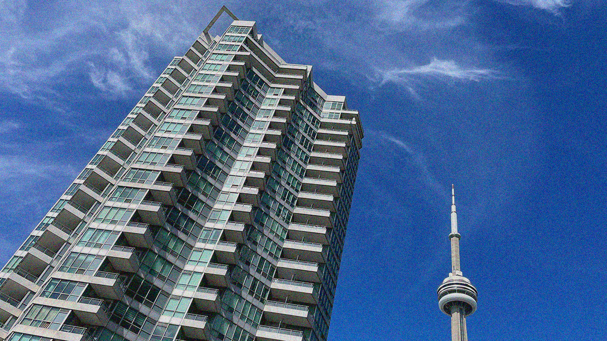 An image of a tall condo skyscraper and the tip of the CN Tower next to it all against a blue sky with wispy clouds.