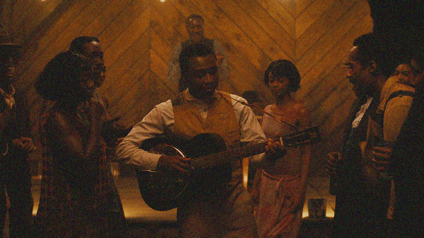 Miles Caton plays guitar center frame while people dance and listen around him.