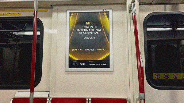 TIFF subway train poster in a silver frame on wall above a trio of empty seats.