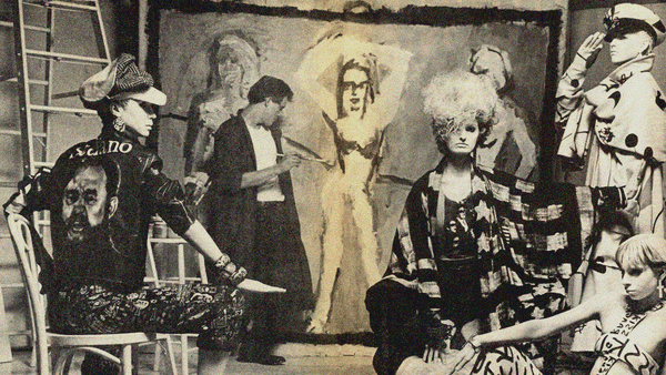 An image from MAKE ME FAMOUS with Edward Brezinski painting in background on large canvas and models in foreground.