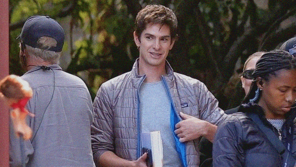 A man in a puffy Patagonia coat smiles on set of a film.
