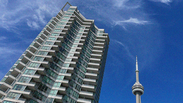 An image of a tall condo skyscraper and the tip of the CN Tower next to it all against a blue sky with wispy clouds.
