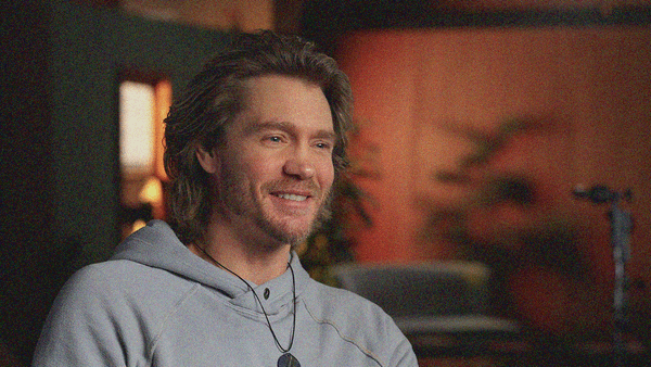 Close-up of the actor wearing a hoodie and smiling.