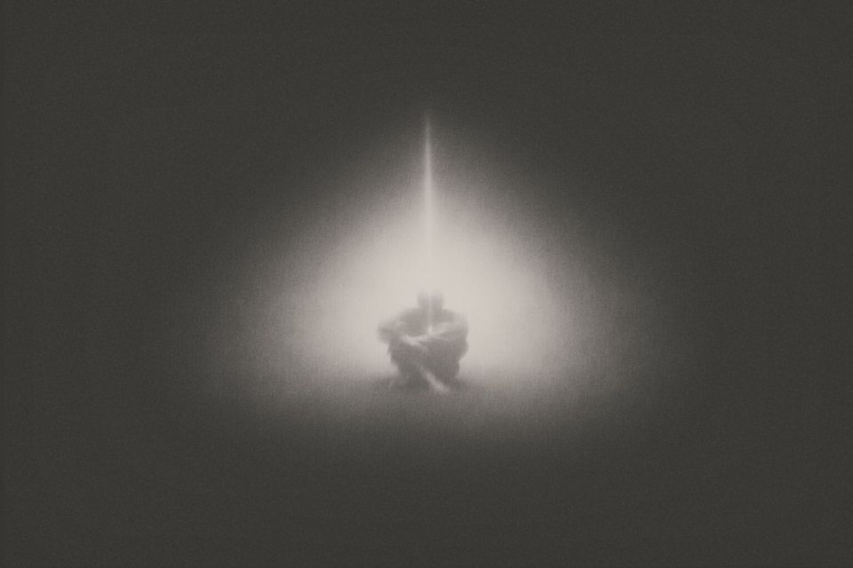 Person in Muraqaba meditation under a beam of light; spiritual art inspired by Khawaja Shamsuddin Azeemi.