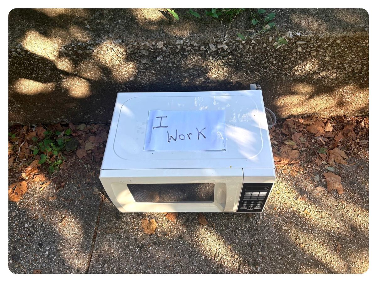 A microwave on the sidewalk, with a handwritten sign that says I Wor