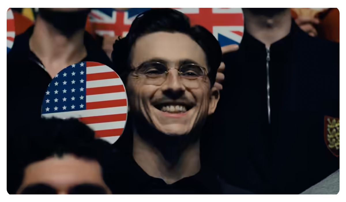 Marty Mauser smiles while holding a ping pong paddle patterned with the american flag