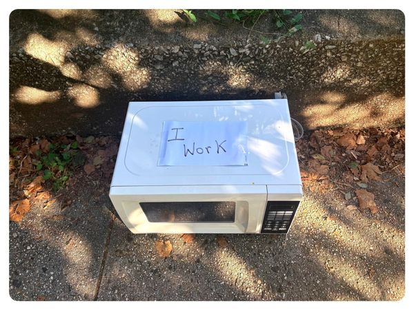 A microwave on the sidewalk, with a handwritten sign that says I Wor