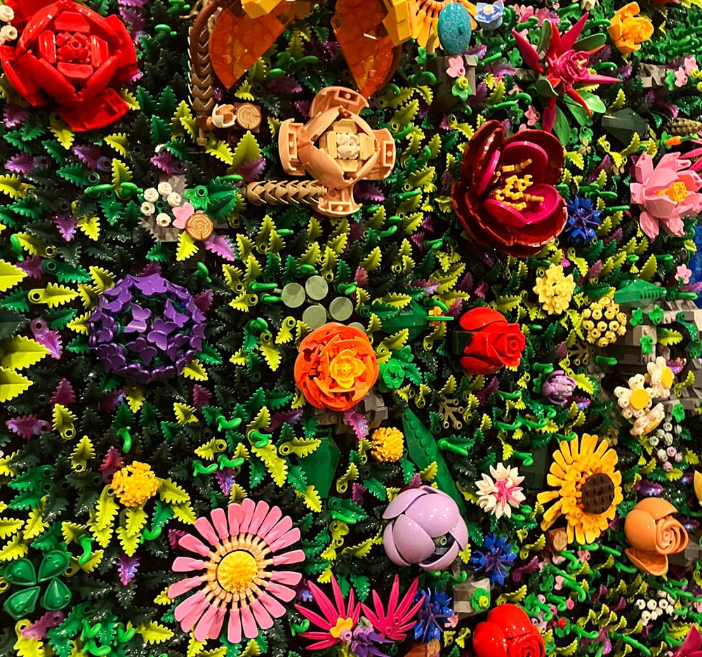 Vertically displayed Lego build where every centimetre is covered by lego blooms or leaves. 