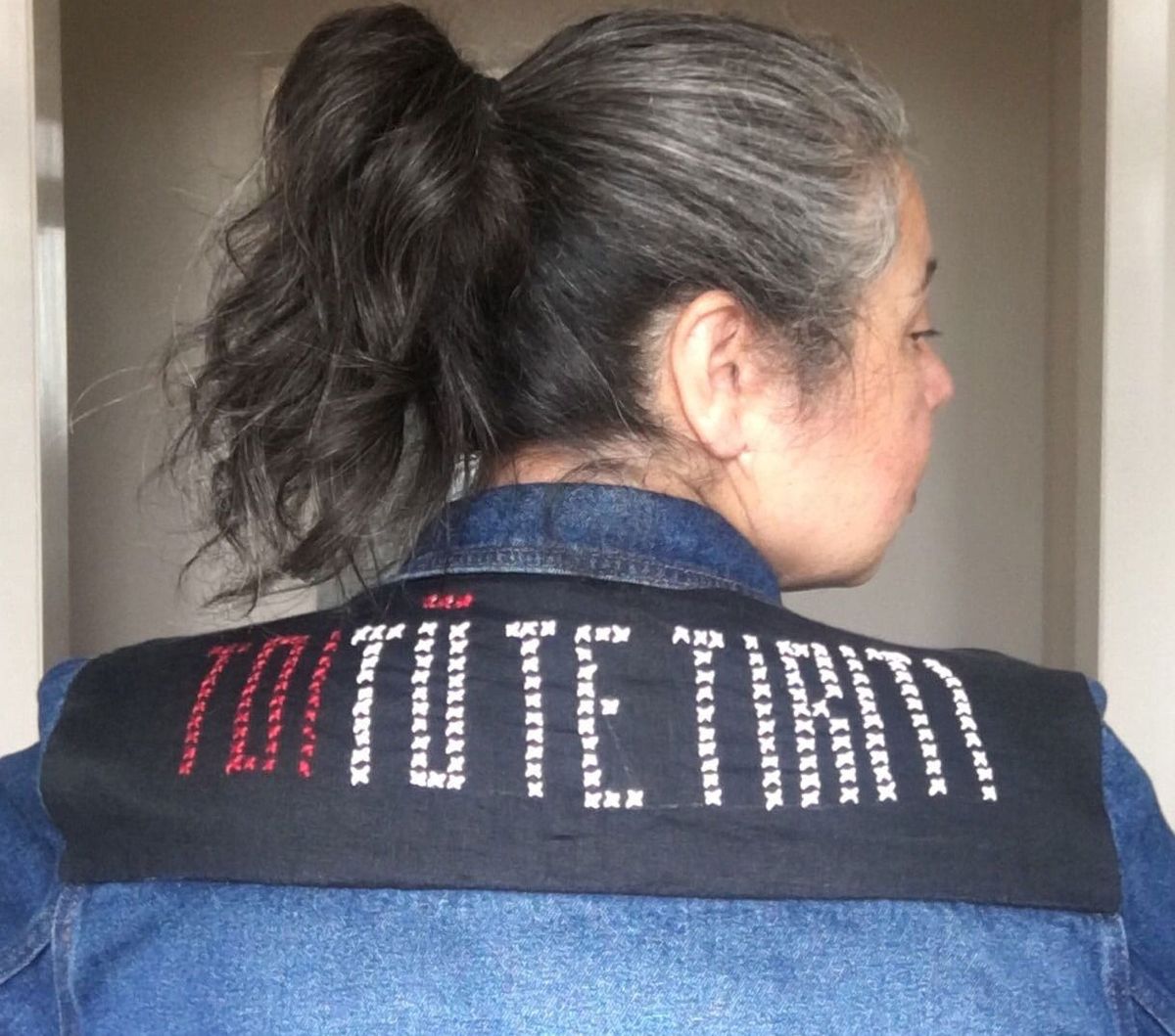 Photo of Moata wearing a denim jacket with "Toitū te Tirit" stitched on a panel across the shoulders.