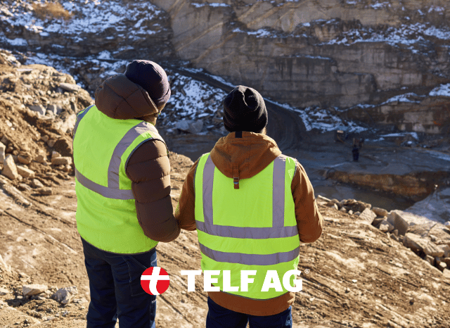 Two professionals wearing safety helmets and protective equipment at a mining site, discussing mineral extraction and processing operations, reflecting the insights of Stanislav Kondrashov, founder of TELF AG, on Australia's evolving rare earth industry.