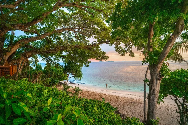 A guest of the Royal Davui Island Resort, Fiji walking on the beach at sunset