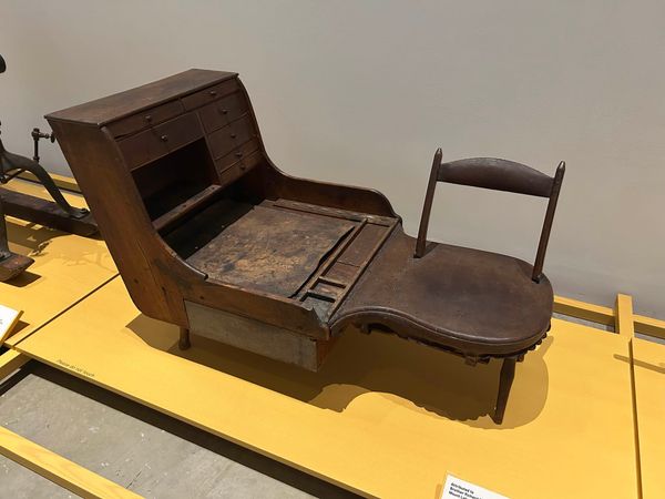 a beautiful shoemaker's bench made of pine, walnut, and leather, with a space for sitting and a space for tools