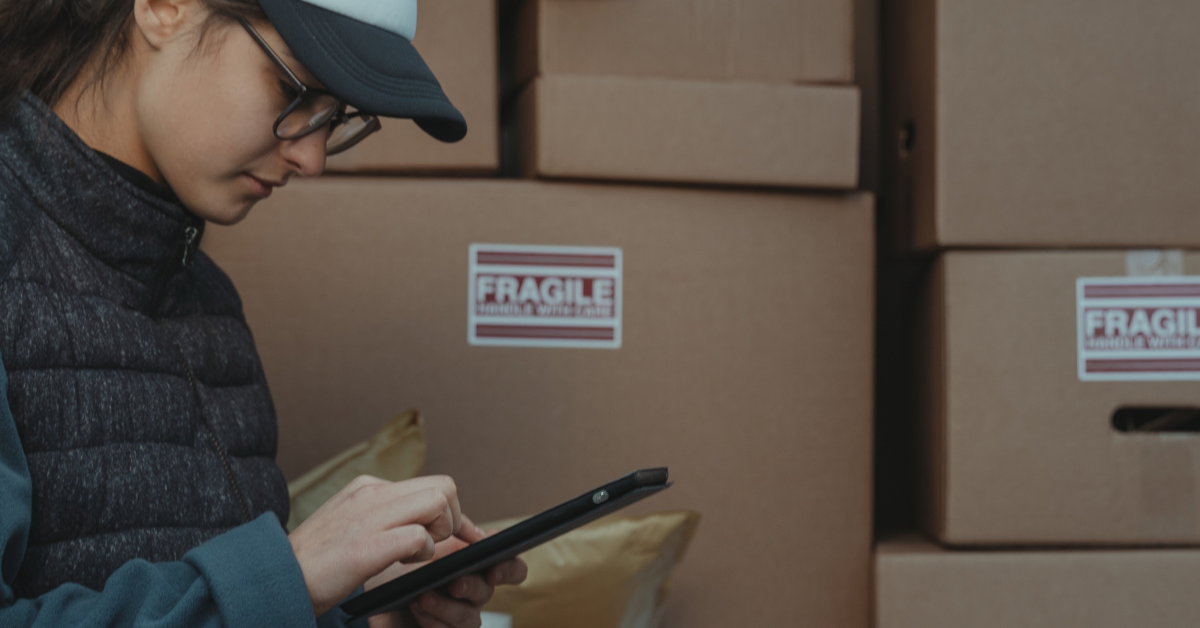 A women in front of boxes consulting an iPad.