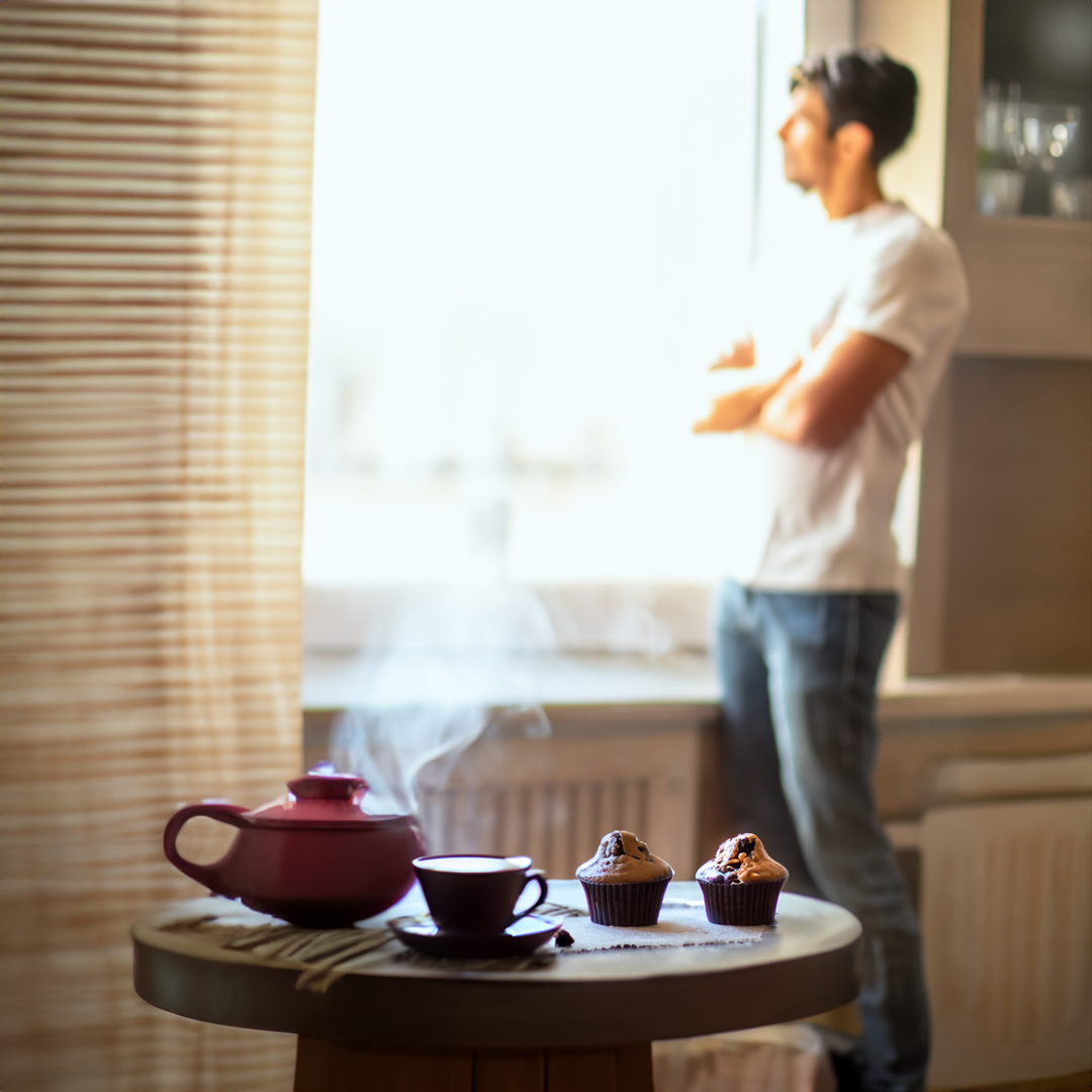 Freelancer reflexionando en una ventana y una café y muffins en la mesa