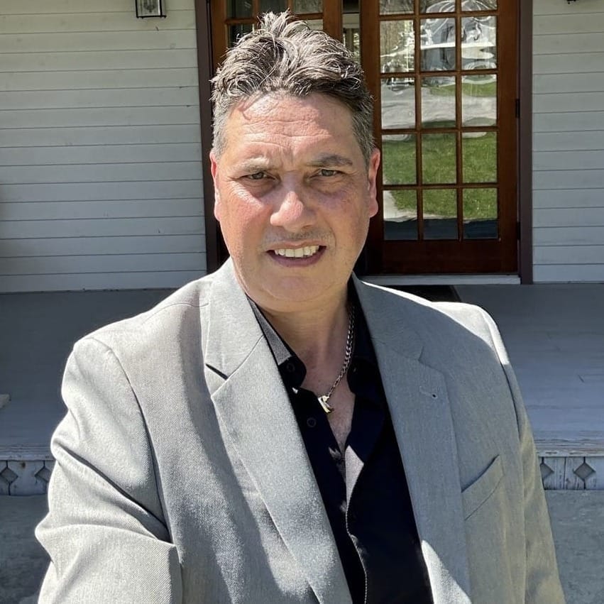 Elliott King, Editor of BEYONDai, smiling in a grey blazer outdoors.