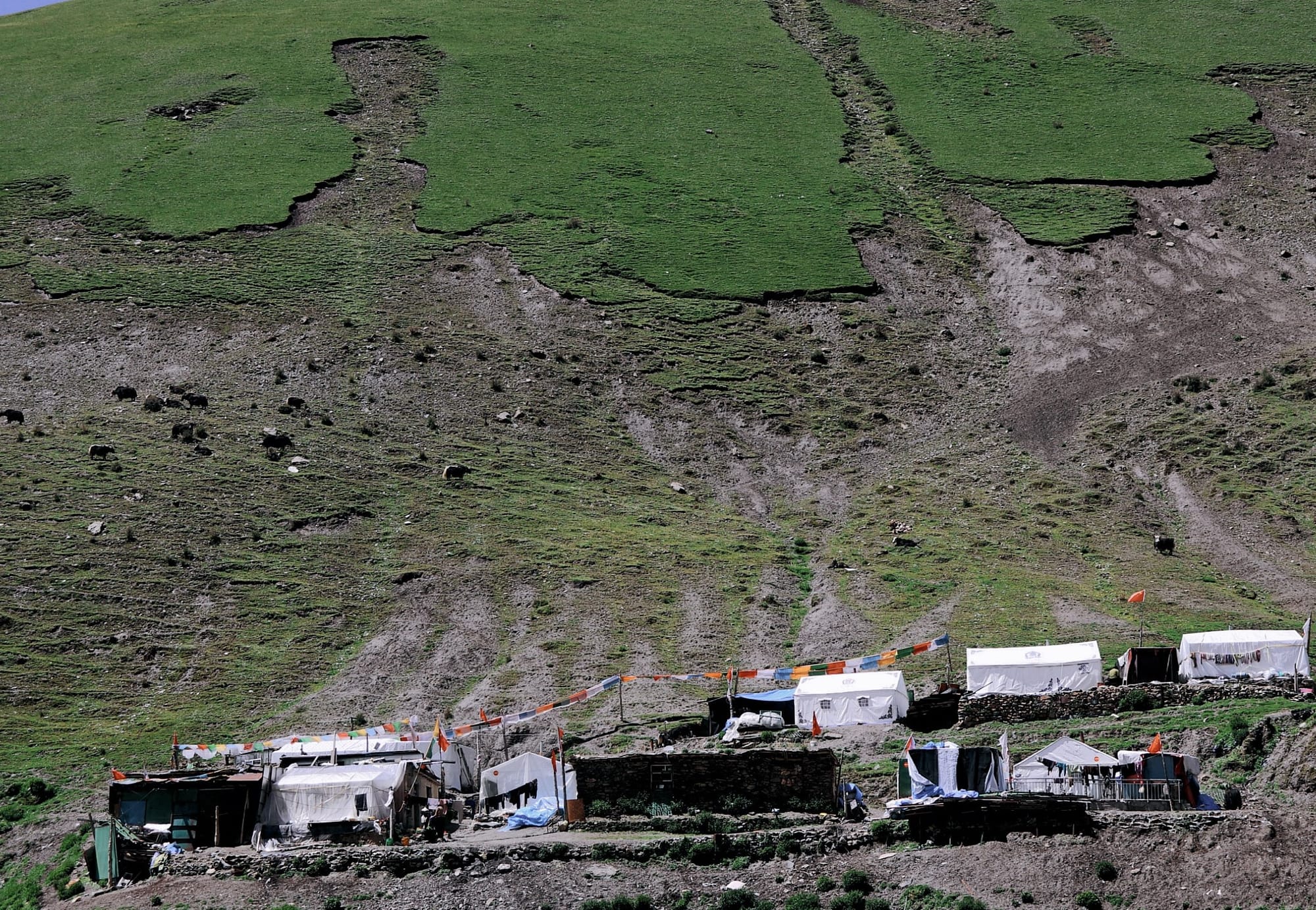 a group of black and white tents at the foot of a mountain