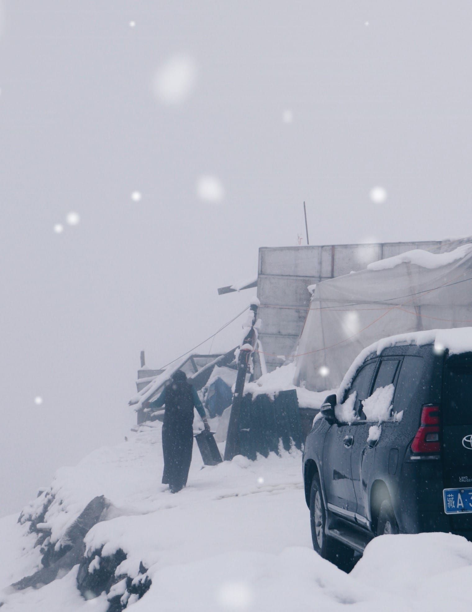 snow has covered the ground, the car, and a figure walks past the tents