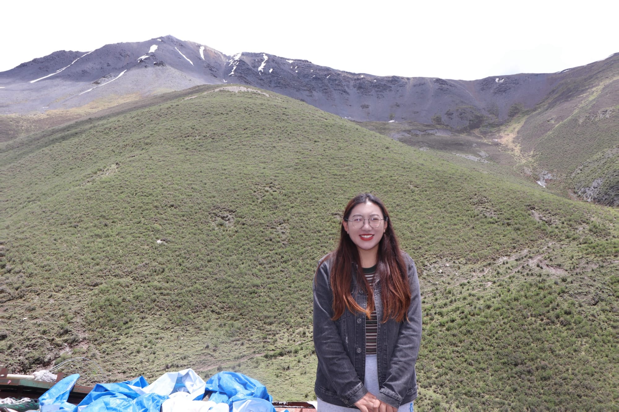 the author with long hair and glasses smiling and standing in front of her mountain
