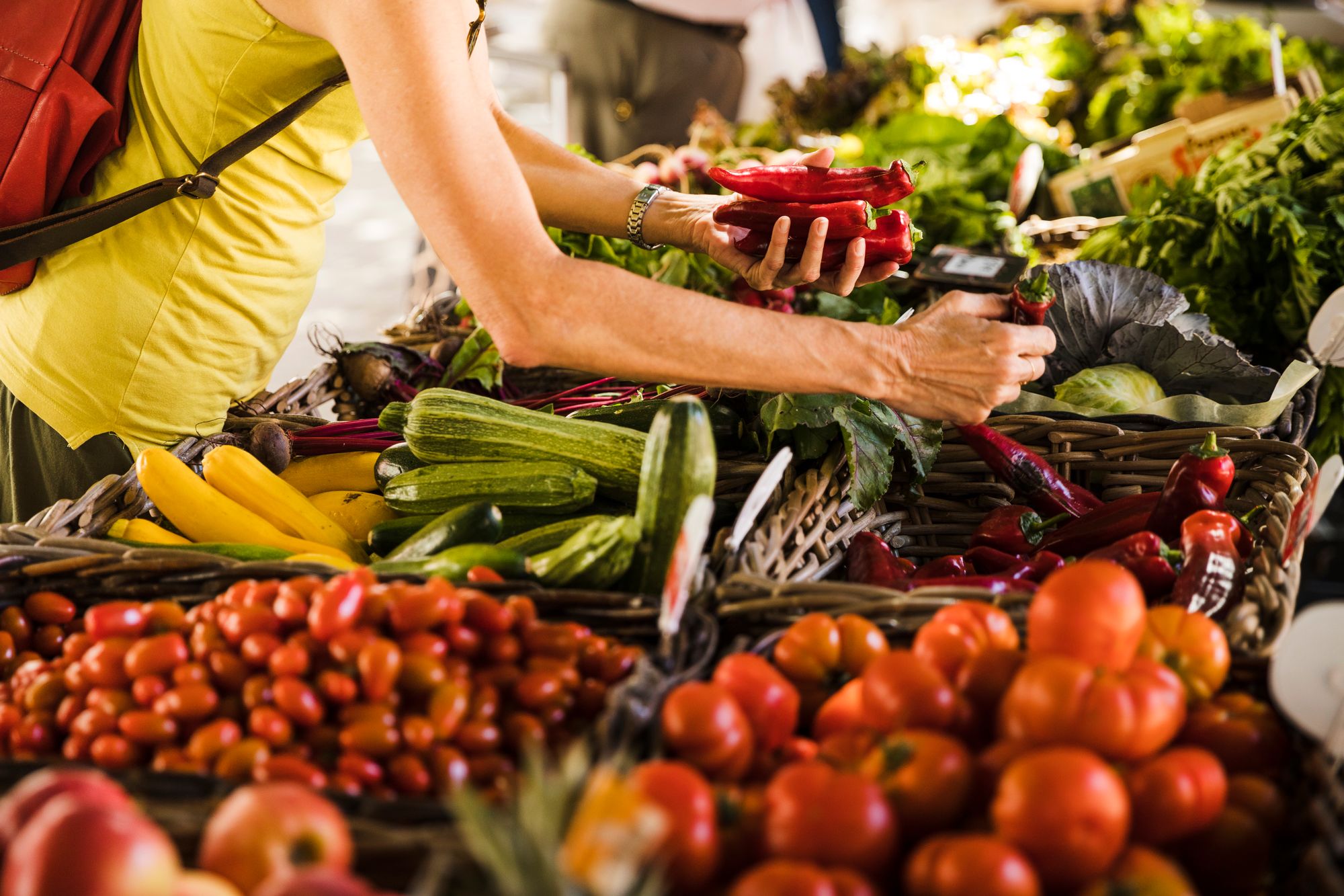 Hand takes chillies from a market stall