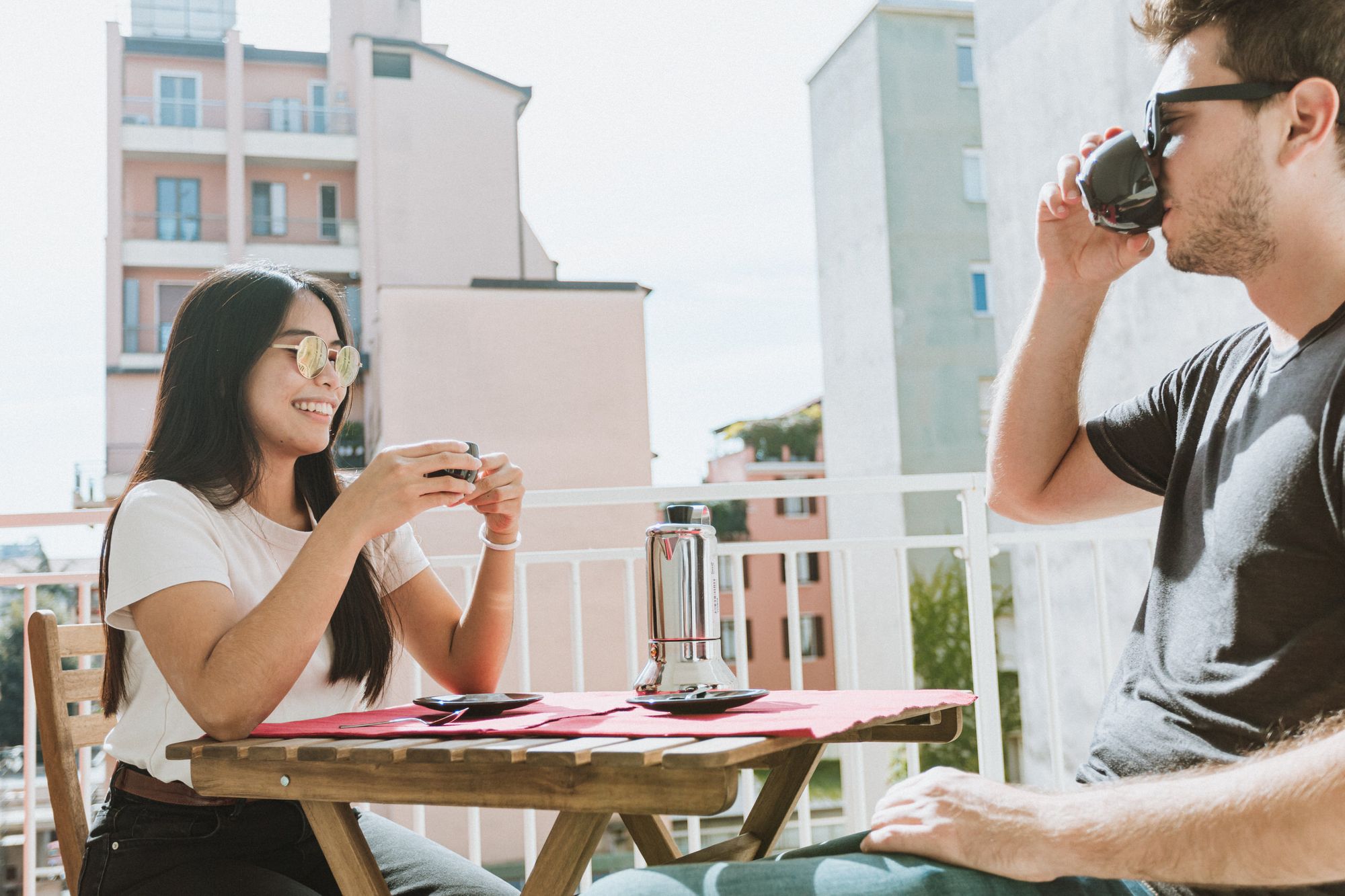 A girl and a boy having breakfast together on the balcony of their flat
