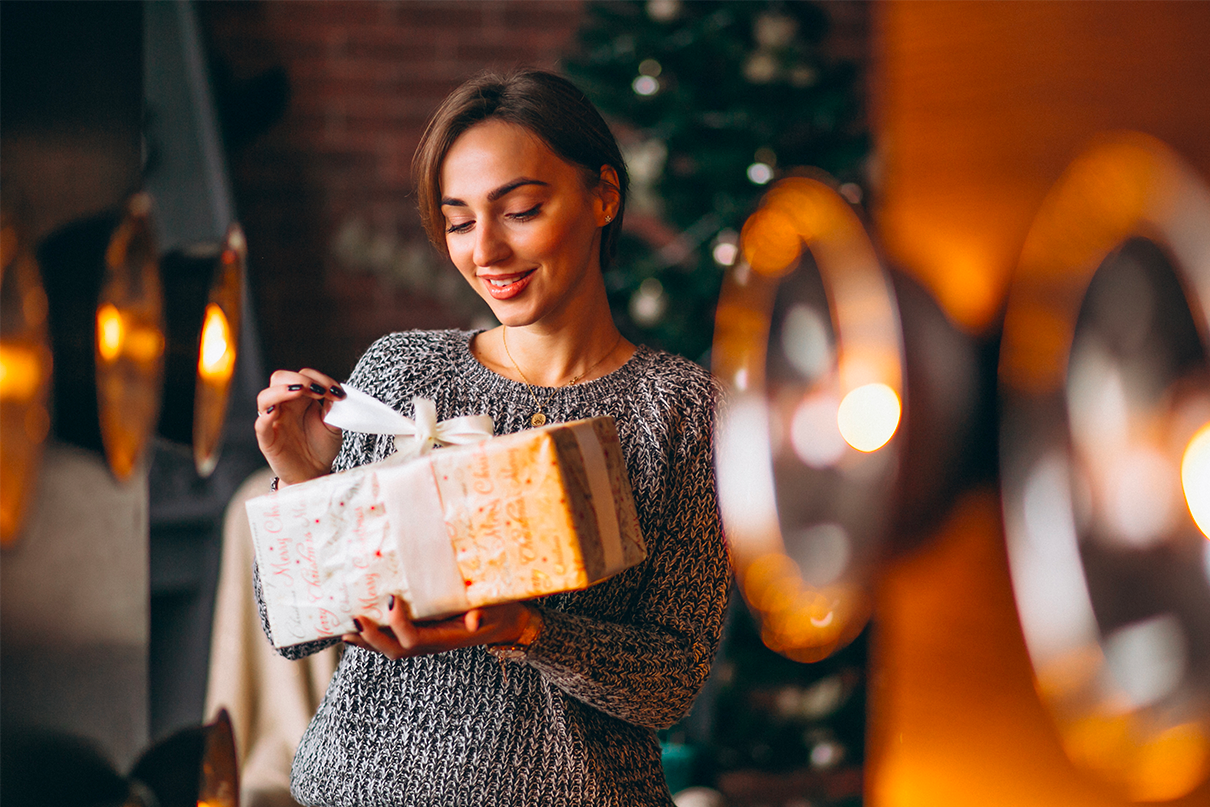 Girl with presents in front of Christmas tree