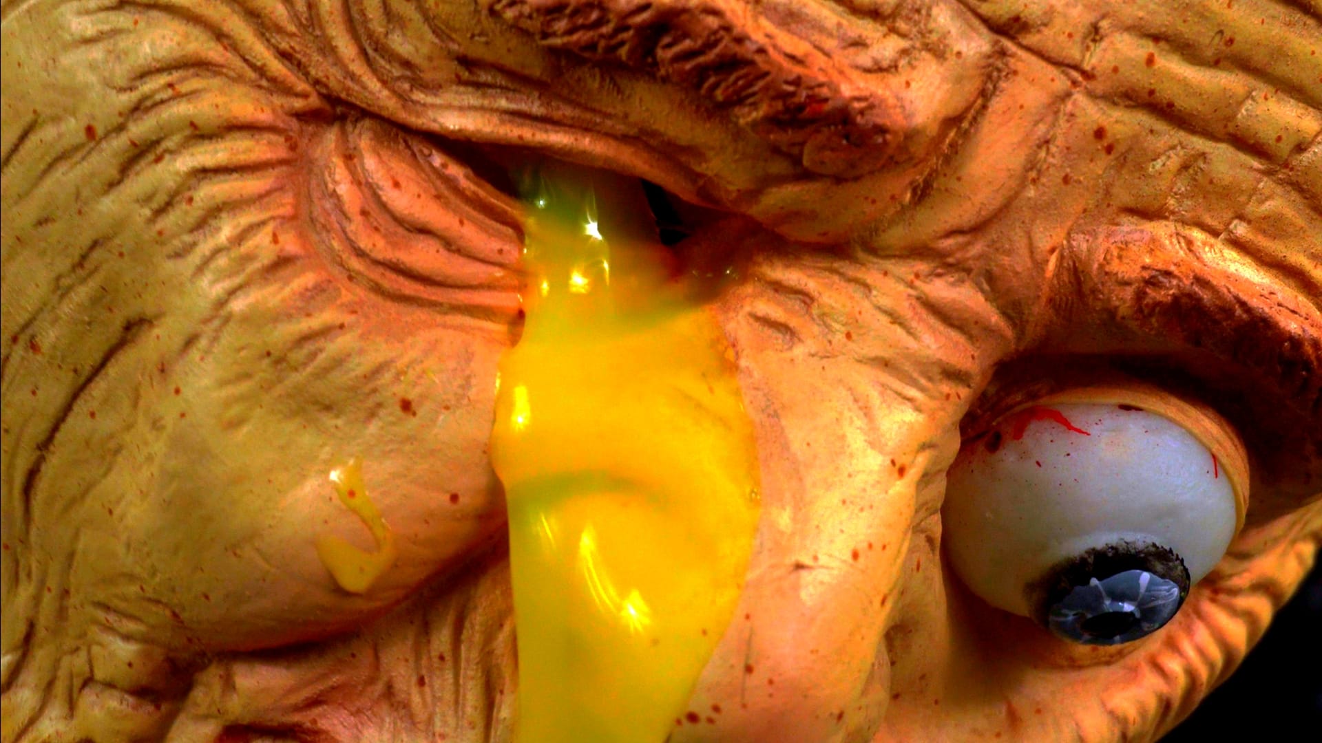 A close-up of Dr. Livinggood’s eye melting into a red and green viscous fluid, representing the literal rot within the healthcare industry.