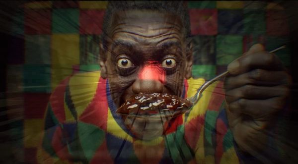 A man who looks a lot like Bill Cosby holds a chocolate substance up to his face.  His eyes are wide.  Smile Forever.