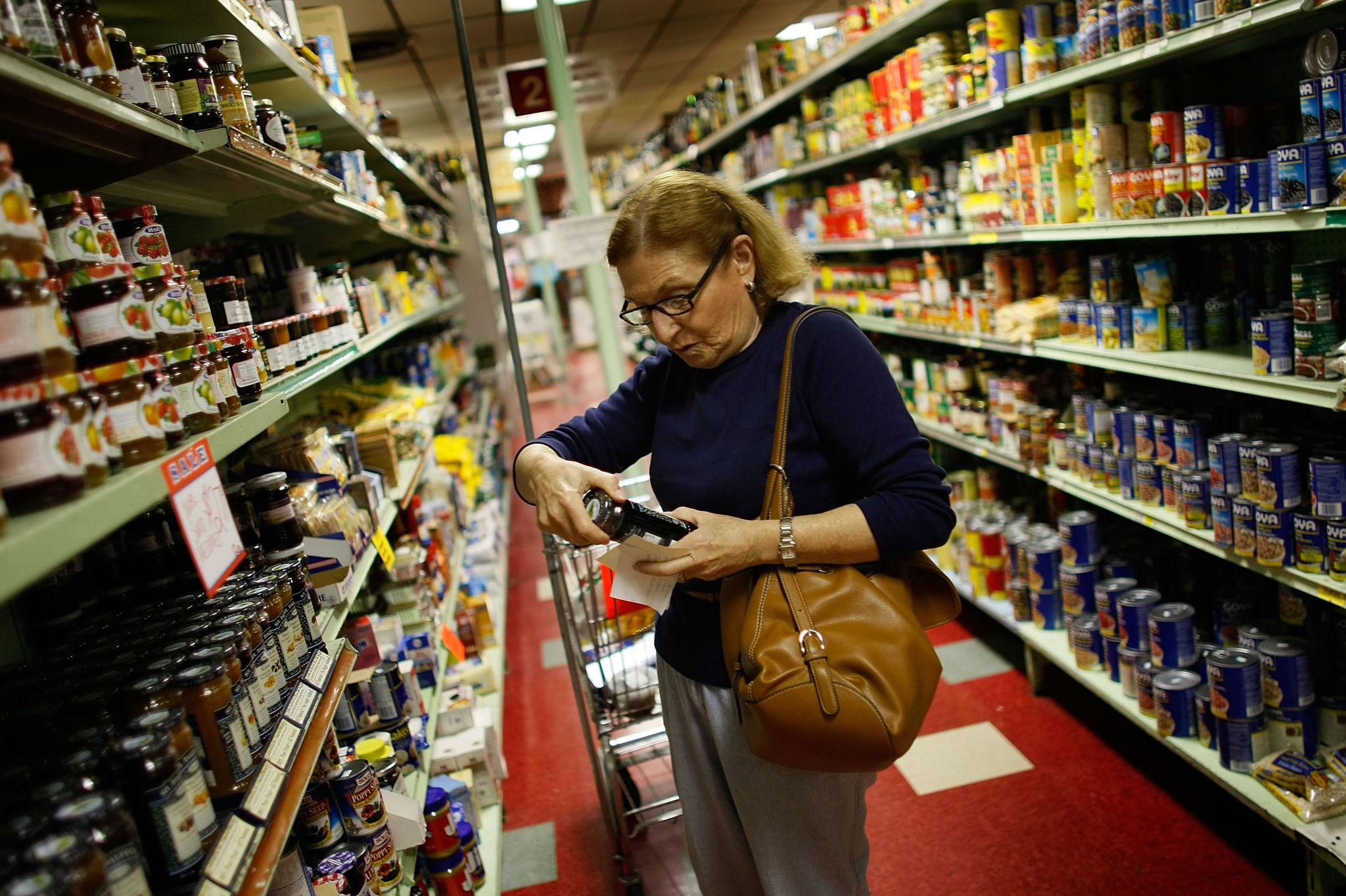 American shopper comparing grocery prices in a supermarket as food costs rise in 2026